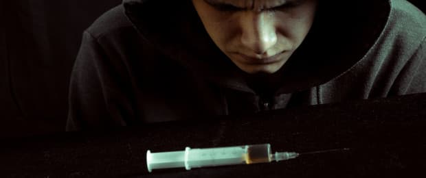 man looking at heroin needle