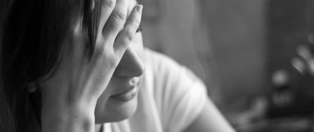 woman with head in hands in pain